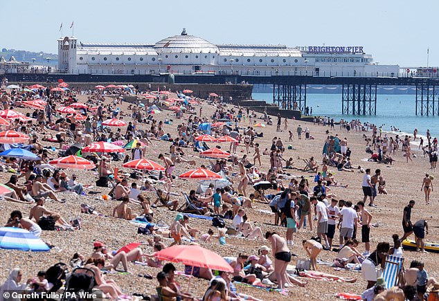 Vista da praia enquanto as pessoas aproveitam o clima quente em Brighton, East Sussex