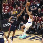 O guarda do New York Knicks, Mikal Bridges (25), chuta enquanto o guarda do Cleveland Cavaliers, James Harden (1), defende.
