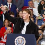 O quarterback do New York Giants, Jaxson Dart, falando em um comício com uma multidão ao fundo.