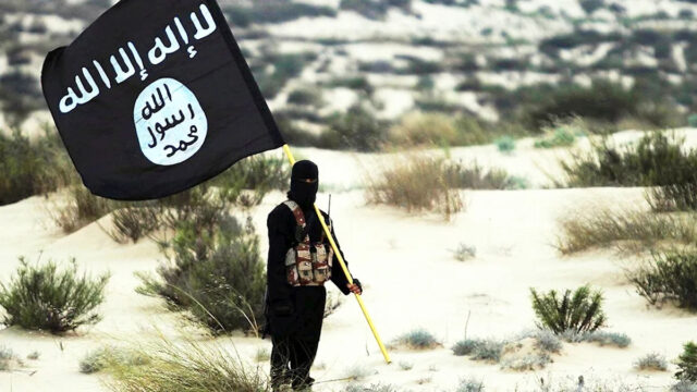 Líder terrorista do ISIS em liberdade após ataque dos EUA Combatente mascarado do Estado Islâmico segura bandeira do ISIS no deserto