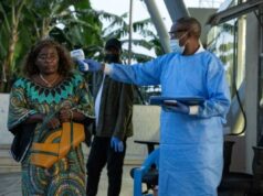 Médico americano confirmou ter Ebola enquanto surto no Congo ultrapassa 300 casos suspeitos Um profissional de saúde congolês com equipamento de proteção azul verifica a temperatura de um viajante na fronteira da Grande Barreira.