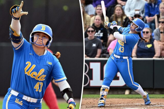 Uma jogadora de softball da UCLA com uniforme azul e capacete levantando a mão enluvada no ar.