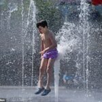 Alfie Thompson-Bell parece ser levantado pela força da água enquanto se refresca no City Park, Bradford