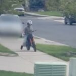 Um menino de capacete andando de bicicleta suja na calçada.