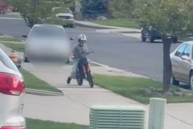 Um menino de capacete andando de bicicleta suja na calçada.