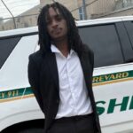 Um homem de terno está na frente do veículo do xerife do condado de Brevard.
