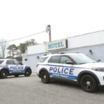 Dois carros da polícia do condado de Suffolk estacionados em frente ao Shore Motor Inn, onde foi feita uma prisão por promover prostituição e tráfico sexual.