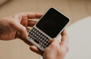 O Clicks Communicator está recebendo um grande aumento de bateria e Android 17 pronto para uso Uma mão segurando o Comunicador Clicks, flanqueado por vistas angulares destacadas.