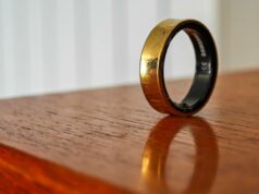 O Galaxy Ring 2 está chegando, mas não este ano Um Samsung Galaxy Ring dourado apoiado verticalmente na borda de uma mesa de madeira