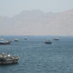 Barcos em uma baía com montanhas ao fundo.