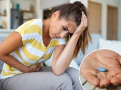 O Viagra pode ajudar com um problema que atinge até 90% das mulheres – mas há um problema Mulher sentada em um sofá, segurando a cabeça e o estômago com dor, sofrendo de enxaqueca e cólicas abdominais.