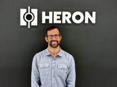 O ex-executivo da Tesla e CEO da Heron Power, Drew Baglino, fundou uma startup de bombas de calor Drew Baglino standing in front of the Heron Power logo.