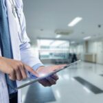 Close-up of a physician's hands holding a tablet, used in a post about healthcare startup Regard