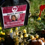 Flowers and signs are seen in a makeshift memorial in front of the home of Nancy Guthrie on February 27, 2026 in Tucson, Arizona.