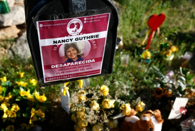 Flowers and signs are seen in a makeshift memorial in front of the home of Nancy Guthrie on February 27, 2026 in Tucson, Arizona.