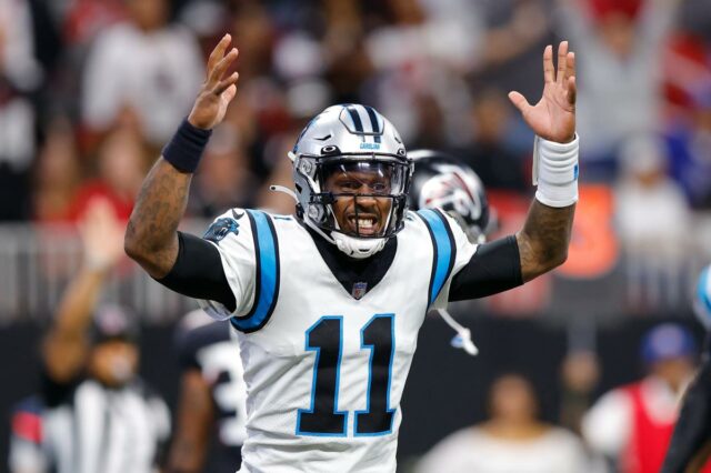 Um jogador do Cleveland Browns segura um uniforme de futebol, olhando por baixo do capacete.