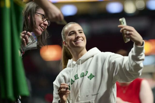 Sabrina Ionescu, que estrelou pelo Oregon Ducks, tira uma selfie com um fã antes da derrota do Liberty por 98-96 para o Fire em 12 de maio de 2026 em Portland, Oregon.