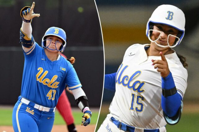 Uma jogadora de softball da UCLA, uniformizada com capacete azul e protetor de queixo branco, levanta a mão direita e aponta.