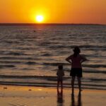 Uma mulher e uma criança observam o pôr do sol na praia de Mindil, em Darwin.