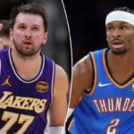 Luka Doncic com uma camisa roxa do Lakers gesticulando com três dedos.
