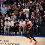 O guarda do New York Knicks, Jalen Brunson # 11, comemorando um arremesso de 3 pontos contra o Cleveland Cavaliers, com fãs torcendo ao fundo.