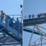 Pessoas evacuando uma montanha-russa por uma escada de metal azul após uma queda de energia.