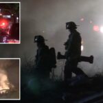 Foto noturna de veículos de emergência, incluindo um caminhão de bombeiros com uma escada estendida, respondendo a um incêndio em um túnel.
