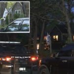 Um carro da polícia estacionado em frente a uma casa com fita amarela de cena do crime no gramado.