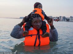 Quase 400 migrantes chegaram ontem ao Reino Unido em seis pequenos barcos, enquanto gangues de tráfico de pessoas aproveitavam o tempo quente Quase 400 migrantes chegaram ontem ao Reino Unido em seis pequenos barcos, enquanto gangues de tráfico de pessoas aproveitavam o tempo quente. Na foto: Um migrante carregando uma criança no mar, espera para embarcar em um barco inflável na praia de Dunquerque