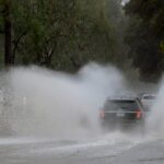 Vehicles drive through a flooded street in Los Angeles on February 13, 2025.