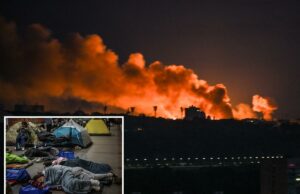Rússia ataca Kyiv com mísseis balísticos após promessa de “punir” a Ucrânia Vista noturna do horizonte de uma cidade com grandes nuvens de fumaça laranja subindo para o céu por trás dos edifícios.