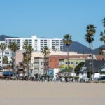O calçadão e os edifícios de Venice Beach, Califórnia, com montanhas ao fundo.