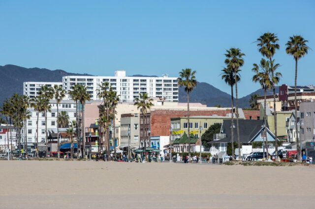 O calçadão e os edifícios de Venice Beach, Califórnia, com montanhas ao fundo.