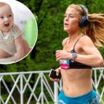 Uma corredora com sutiã esportivo preto e shorts azuis, usando fones de ouvido e um smartwatch, corre com os cabelos voando, carregando um telefone.
