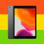 Uma mulher ruiva usa um tablet, tocando a tela com o dedo.