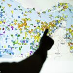 TOPSHOT – Uma ilustração fotográfica tirada em Nicósia em 4 de maio de 2026 mostra uma pessoa em frente a uma grande tela exibindo os movimentos de navios no Estreito de Ormuz em um site de rastreamento de navios. A marinha iraniana disparou “tiros de alerta” contra navios de guerra dos EUA no Estreito de Ormuz em 4 de maio, informou a mídia estatal, depois que os militares americanos enviaram cruzadores para o Golfo como parte de um plano para ajudar a saída de navios comerciais presos. Anteriormente, o presidente dos EUA, Donald Trump, tinha anunciado um plano para guiar navios de países neutros para fora do Golfo, dizendo que era um esforço humanitário para ajudar as suas tripulações retidas. (Foto da AFP via Getty Images)