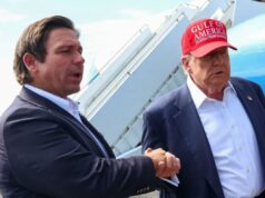 Trump avalia nomeação de gabinete para o governador da Flórida, Ron DeSantis O governador da Flórida, Ron DeSanti, dá as mãos ao presidente dos EUA, Donald Trump, que usa um chapéu vermelho que diz