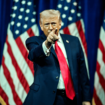Donald Trump aponta durante aparição em estilo de campanha cercado por bandeiras americanas em meio ao debate sobre os mercados de previsão e a regulamentação da CFTC.