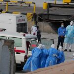 Profissionais de saúde com equipamento de proteção evacuam pacientes do MV Hondius para uma ambulância no porto da Praia, Cabo Verde, na quarta-feira