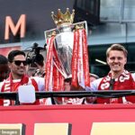 Mikel Arteta e Martin Odegaard seguram o troféu da Premier League em cima do ônibus