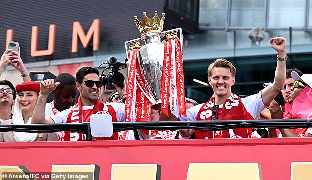 Mikel Arteta e Martin Odegaard seguram o troféu da Premier League em cima do ônibus