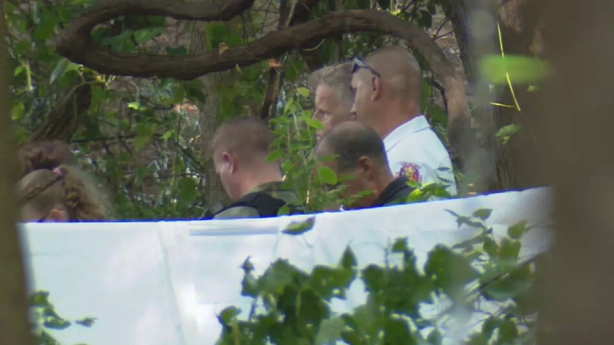 WJLA - FOTO: Um policial do estado de Maryland, em 21 de junho de 2026, perto do local dos destroços de um pequeno avião que caiu e matou três pessoas a bordo em Bowie, Maryland.