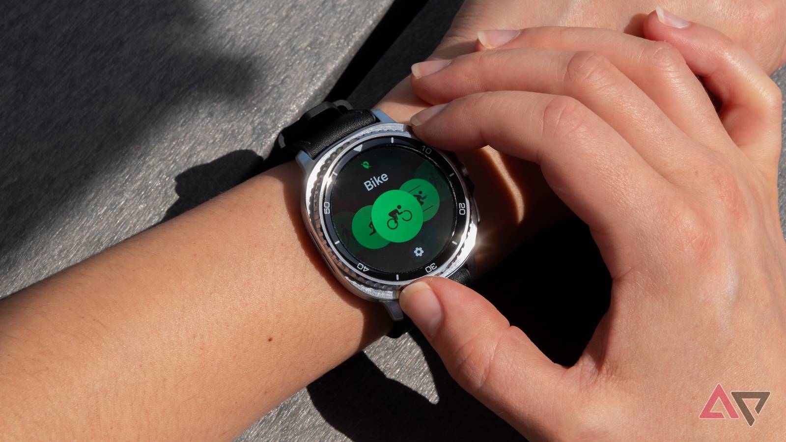 Imagem teaser escura do Samsung Galaxy Watch Series, mostrando três silhuetas de smartwatch com bordas brilhantes em um fundo azul.