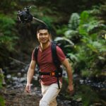 Man hiking in a forest wearing Odyssey camera pack
