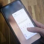Mascote Android com braços robóticos segurando engrenagens em um fundo verde.