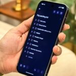 Homem trabalhando em um laptop ao lado de um grande logotipo 3D do Google Keep e de uma lista de verificação flutuante.