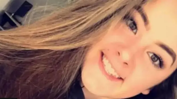 Selfie de Emily Moore. Ela está sorrindo para a câmera. Ela tem longos cabelos castanhos. A foto é tirada em um ângulo de forma que o topo de sua cabeça fique no canto superior direito, enquanto seu cabelo cai para baixo. Ela parece genuinamente feliz.