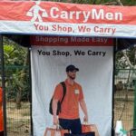 Os fundadores Ritu Kandari Srivastava (em sari verde) e Kanishka Malhotra (em calças pretas e blusa vermelha) no quiosque CarryMen no mercado Lajpat Nagar