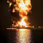 Um petroleiro queima após ser atingido por um ataque iraniano na zona de transferência entre navios no porto de Khor al-Zubair, perto de Basra, Iraque, na noite de quarta-feira, 11 de março