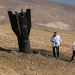 Foto de Ghaith Alsayed / AP - FOTO: Agricultores borrifam água em um campo agrícola queimado próximo a um projétil perto da cidade de Najha, Síria, 8 de junho de 2026, depois que destroços de lançamentos de mísseis iranianos durante o conflito Irã-Israel caíram na área.